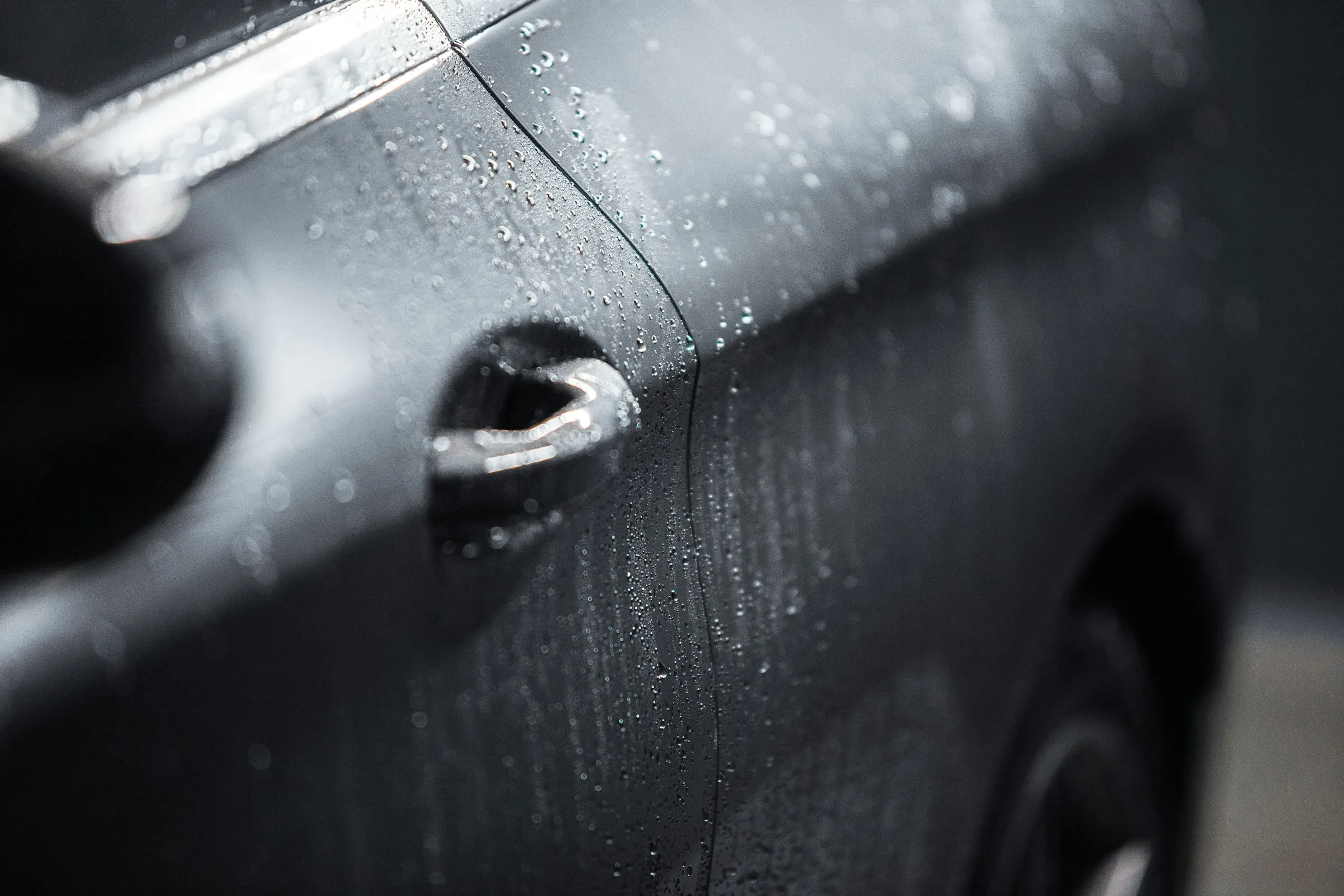 Primer plano de la pintura de un auto limpio, con el agua perlando